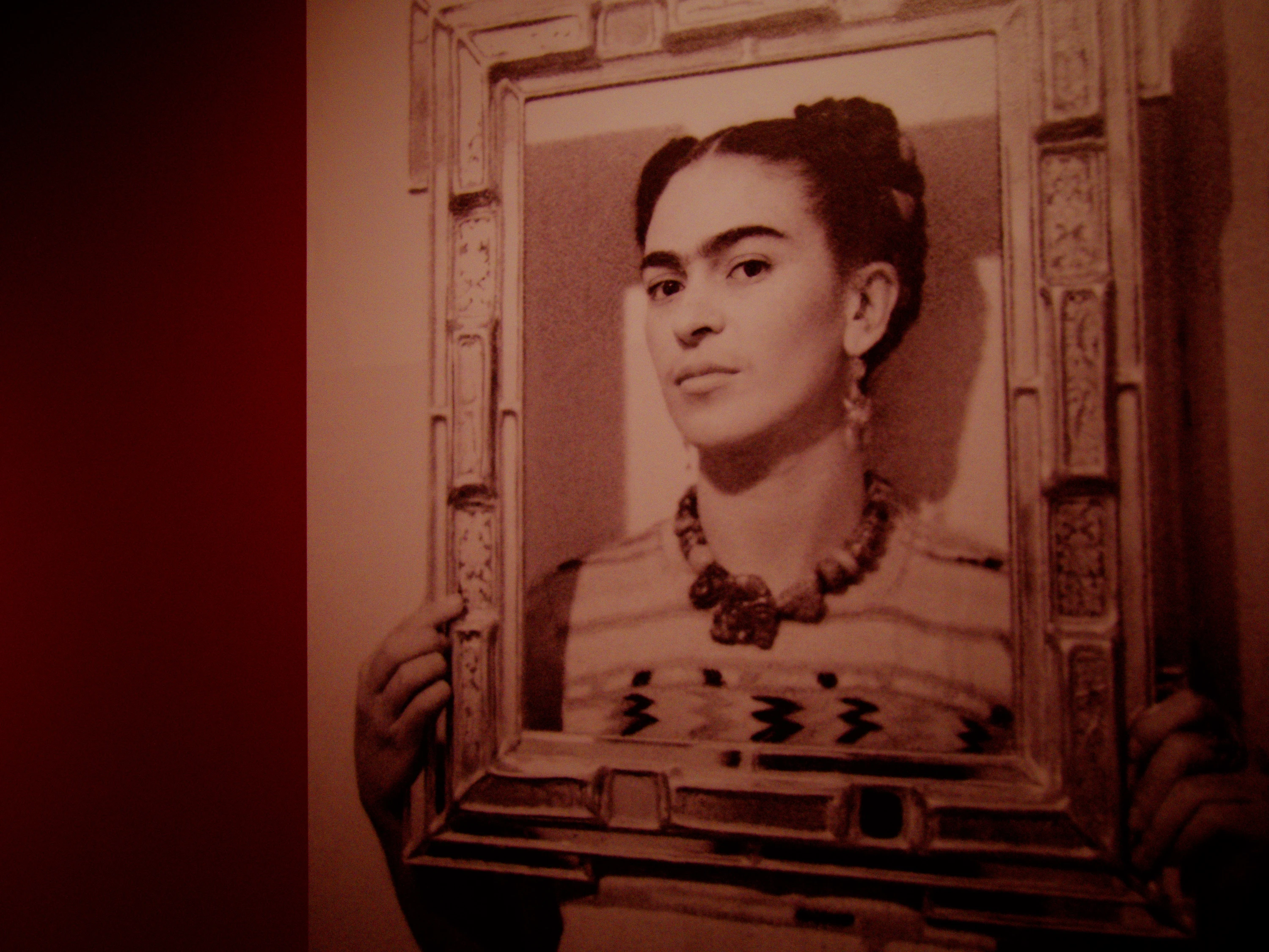 Photograph of Frida Kahlo holding an empty frame around her face